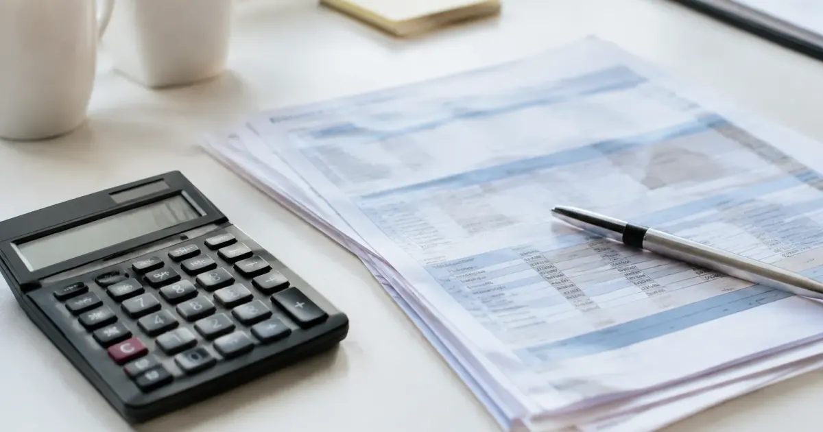 Calculatrice et documents de paie posés sur bureau blanc