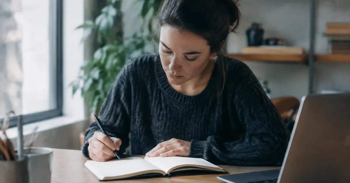Personne assise au bureau notant idees dans carnet